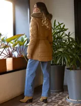 Campera de abrigo negra marca Michael Kors, con capucha desmontable con borde de piel sintética, cierre central con botones a presión y cierre oculto, bolsillos delanteros con cierre, puños elastizados, cintura con pasadores y cinto elastizado con hebilla.