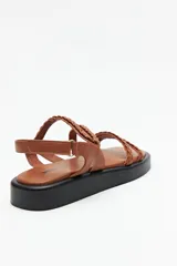 Sandalias color marrón con tiras trenzadas y ajuste de velcro en el talón. Plataforma de 3cm de alto y suela negra.
