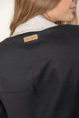 Blazer azul de lino con corte entallado, cuello y solapas combinadas en color gris, cierre con botón de nácar, bolsillos laterales y tajo en la espalda.