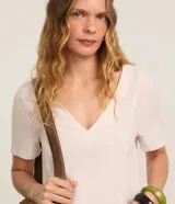 Vestido corto de corte recto y escote en V, color beige claro con estampado de paisaje tropical con palmeras en la parte inferior, mangas cortas y bolsillos laterales. Marca Marfinno.