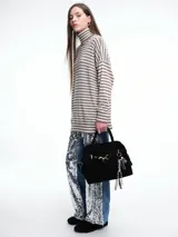 Polera de tejido de punto con diseño de rayas horizontales en tonos marrón y negro, cuello alto, mangas largas con hombros caídos y corte holgado.