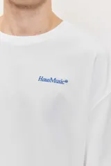 Remera blanca de manga corta, corte oversize, con estampa en la espalda de una flor sobre fondo difuminado verde y blanco.