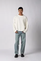 Sweater de punto color blanco con diseño de textura combinada, presentando un lado liso y otro con tejido trenzado. Posee cuello redondo, mangas largas y un corte relajado.