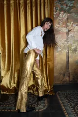 Pantalón dorado de corte acampanado con aberturas laterales en el ruedo.