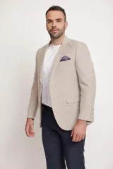 Blazer beige de corte slim fit, con solapas de muesca, cierre de dos botones, dos bolsillos delanteros con solapa y un bolsillo de parche en el pecho con pañuelo de bolsillo estampado.