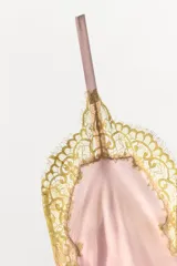 Vestido midi de satén en color rosado, con escote en pico y tirantes finos. Presenta detalles de encaje en color dorado a contraste en el escote y en el ruedo.