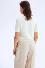 Buzo de punto fino suave con cuello redondo y manga corta. Presenta terminaciones acanaladas en el cuello, puños y bajo.