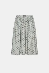 Falda midi de tiro medio, color gris claro con estampado de lunares negros. Presenta cintura ajustable con lazada y bolsillos laterales ocultos.