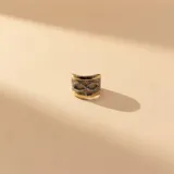 Anillo ancho de plata y oro con diseño central de símbolo de infinito decorado con circonias y textura rugosa en el fondo.