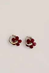 Aros tipo argolla pequeña con dije colgante en forma de flor de color bordó.