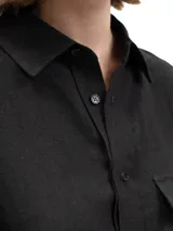 Camisa unisex de lino con mangas tres cuartos, cuello clásico, cierre frontal con botones y un bolsillo aplicado en el pecho.