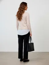 Buzo combinado con torso de tejido de punto fino en color negro y detalles de cuello y ruedo en gasa blanca que simulan una camisa debajo. Presenta escote en V y mangas largas.