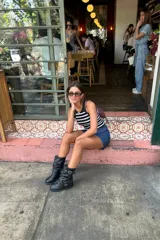 Bota de cuero negro con caña media arrugada, dos correas con hebillas plateadas y taco bajo.