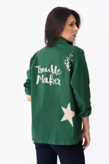 Campera verde militar de algodón con mangas largas y cuello camisero. Estampado en la espalda con la frase "Trouble Maker" y una estrella.