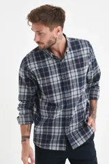 Camisa de manga larga con estampado de cuadros en tonos azul, gris y líneas finas en color naranja. Presenta cuello con botones, cierre frontal abotonado y un bolsillo en el pecho.