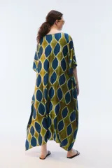 Kaftan maxi amplio de color amarillo, con escote redondo, mangas cortas y ruedo irregular. Presenta un diseño estampado a cuadros con efecto teñido.