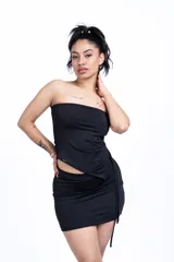 Conjunto negro de top tipo tubo y minifalda ajustada con cordón lateral. El top es strapless y la falda es de tiro bajo.