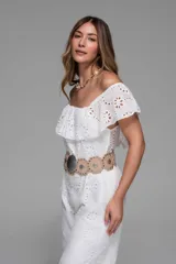 Mono largo blanco de broderie con escote off-shoulder con volados y cinturón marrón con hebilla circular.