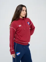 Canguro deportivo Umbro del Club Nacional de Football, color bordó, con capucha ajustable con cordón, bolsillo tipo canguro y costuras visibles en contraste. Presenta el logo de Umbro y el escudo del club bordados en el frente.