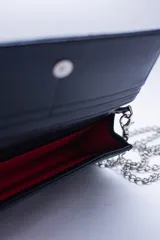 Cartera de cuero color marrón claro, con diseño capitoneado y cadena metálica plateada removible. Tiene ranuras interiores para tarjetas y documentos, y forro textil rojo.