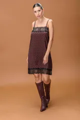 Vestido lencero de satén con estampado de lunares, breteles finos regulables y detalles de puntilla negra en el escote y el ruedo.