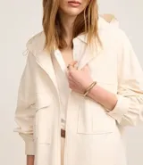 Campera oversized color beige con capucha ajustable, cierre frontal con cremallera, bolsillos cargo delanteros y puños con pliegues.