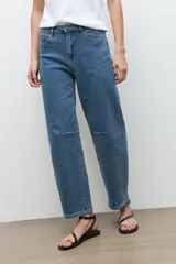 Jean barrel azul de tiro medio, con diseño de perneras curvadas y costuras decorativas a la altura de las rodillas.