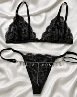 Conjunto de lencería negro de encaje, compuesto por un bralette triangular y una tanga regulable con tiras laterales. Incluye una cadena plateada decorativa con letras metálicas que forman la frase "Feliz Cumple".