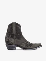 Bota texana corta de cuero color gris oscuro o negro desgastado, con bordados florales en relieve en el empeine y caña. Posee punta afilada y taco bajo.