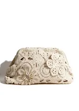 Cartera clutch color beige de crochet con diseño floral y aplique de caracoles en el centro de una de las flores.