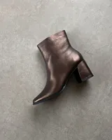 Botín de cuero color bronce con puntera fina y taco geométrico.