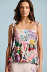 Blusa sin mangas de escote cuadrado, con tirantes finos ajustables mediante lazos en los hombros. Presenta un estampado floral colorido sobre base rosada y corte holgado.