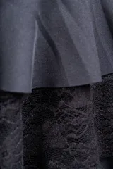 Minifalda negra con cintura alta, confeccionada en tela de punto con volados y encaje.