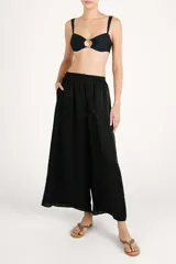 Pantalón fluido de corte ancho, color negro con sutil acabado brillante, cintura elástica y diseño holgado.
