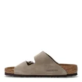 Sandalias Birkenstock modelo Arizona de dos tiras ajustables con hebillas metálicas. Confeccionadas en gamuza color taupe, cuentan con plantilla anatómica de corcho y suela de goma antideslizante.