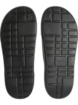 Ojotas tipo slide negras, con tira ancha que presenta el logo 'CK' en relieve en el lateral. La plantilla es contorneada con textura acanalada para mayor agarre.