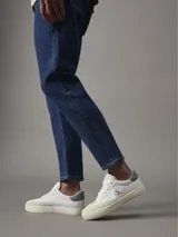 Zapatillas urbanas Calvin Klein Jeans, color blanco con logo CK en dorado y detalle en celeste en el talón.