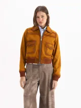 Campera bomber confeccionada en gamuza color tostado, con cierre frontal, bolsillos aplicados con solapa en el pecho y puños y cintura tejidos en marrón oscuro.