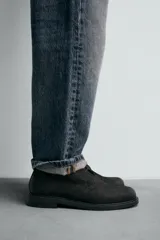 Bota de caña baja con cordones, confeccionada en piel con acabado abatanado. Presenta horma redonda y suela con ligero tacón.