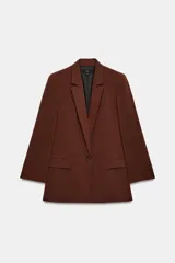 Blazer marrón de cuello solapa con muescas, manga larga y bolsillos de vivo con solapa. Cierre frontal con un botón.