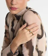 Set de tres anillos dorados de metal con efecto bold, uno texturizado y dos lisos con diferentes formas.