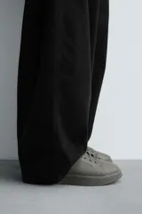 Zapatillas urbanas de cuero sintético negro, con cordones y suela gruesa monocolor.