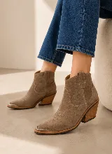 Bota corta estilo western de cuero color marrón, con taco cuadrado de madera y puntera metálica. Presenta costuras decorativas en el empeine y laterales.
