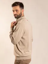 Sweater de punto en color gris claro, con cuello alto y medio cierre frontal. Presenta puños y ruedo acanalados para un ajuste cómodo.