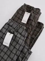 Pantalón sastrero de corte recto y tiro medio-alto, con estampado de cuadros en tonos grises y marrones. Presenta una cintura elástica que aporta comodidad y una textura de tela abrigada.