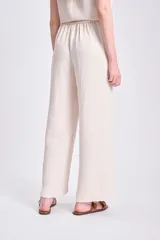 Pantalón de vestir color crudo, de corte palazzo y tiro alto.