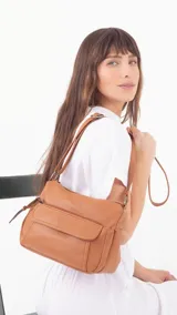 Bandolera de cuero sintético con textura granulada, color marrón. Cuenta con un compartimento principal con cierre, un bolsillo frontal con tapa y bolsillos laterales. Incluye correa larga ajustable para llevar al hombro o cruzada.