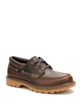 Zapato de cuero color marrón oscuro, estilo náutico, con cordones y suela de goma color caramelo. Presenta costuras decorativas en la puntera y ojales metálicos.