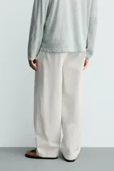 Pantalón barrel fit de hombre, confeccionado en denim de algodón color crudo. Presenta cintura con pliegues frontales, bolsillos laterales y cierre con cremallera y botón.