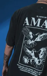 Remera de manga corta con cuello redondo y calce oversize, confeccionada en algodón premium con efecto de lavado nevado. Presenta una estampa gráfica en la espalda con diseño de palomas y texto alusivo.